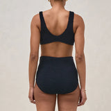 Person wearing a black bikini set on a beige background