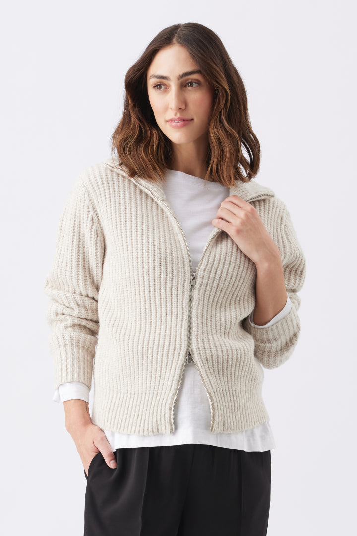 Chunky Zip Knit Maternity Cardigan (Oat) | Ripe Maternity Woman wearing a beige ribbed knit cardigan over a white shirt on a light gray background