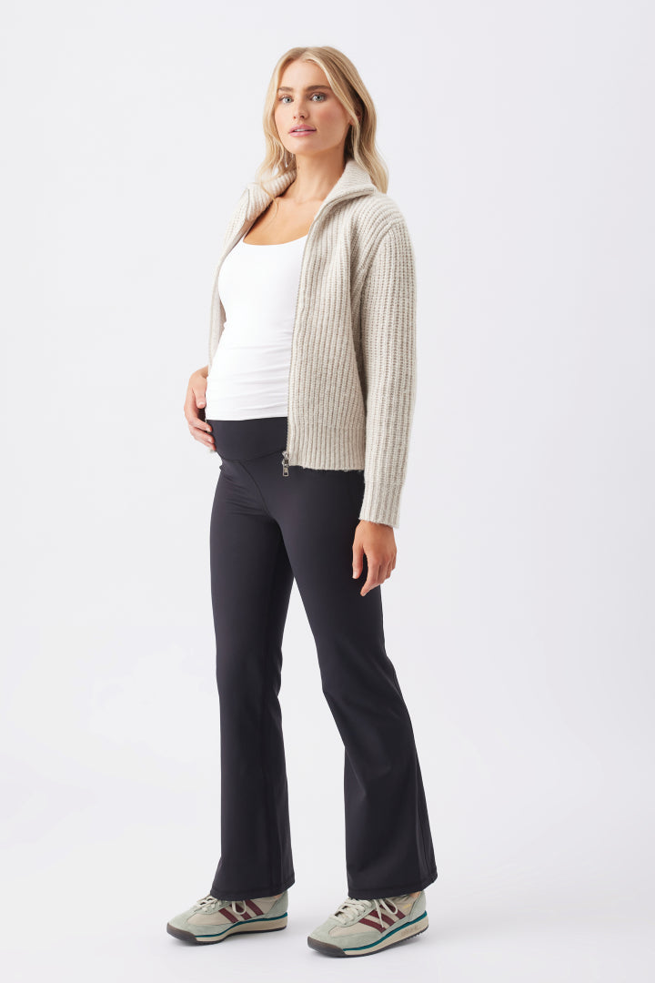 Chunky Zip Knit Maternity Cardigan (Oat) | Ripe Maternity Woman wearing a beige cardigan, white top, and black pants on a white background