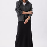 Woman wearing a gray cardigan over a black dress on a white background