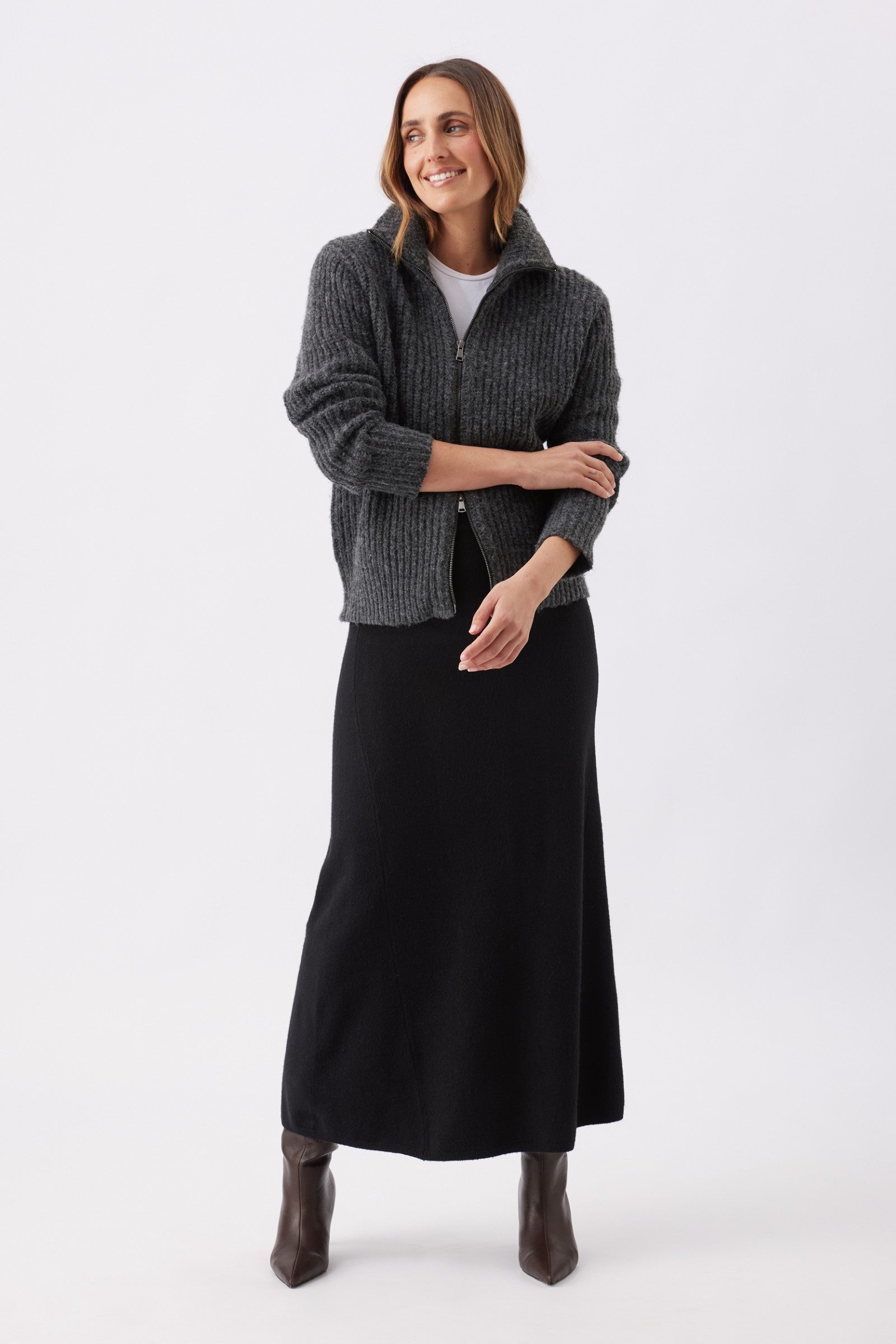 Woman wearing a gray cardigan over a black dress on a white background