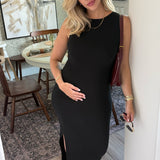 Woman in a black dress standing in a room with a painting on the wall.