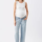 A woman modeling a white sleeveless tank top and light-wash wide-leg jeans against a plain white studio background.