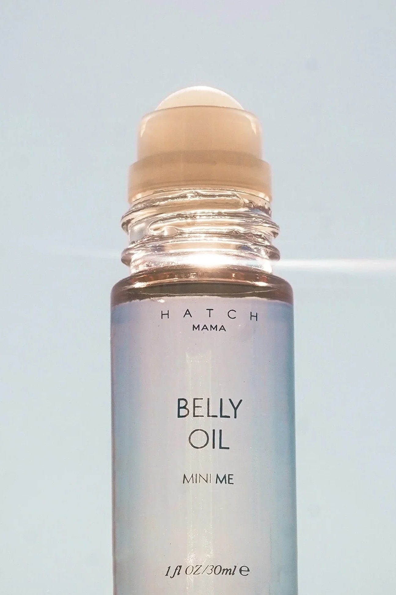 Belly oil bottle with roller ball on a light blue background